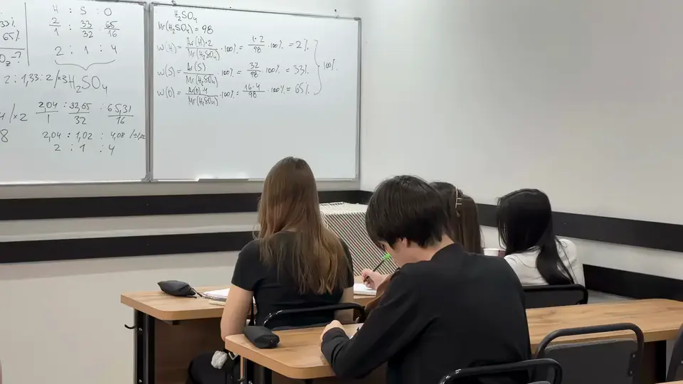Занятие в классе NotaBene: ученики решают задачи в тетрадях, на доске — расчёт по химии