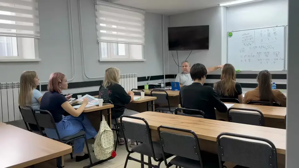 Занятие в классе NotaBene: преподаватель объясняет тему у доски, ученики слушают за партами